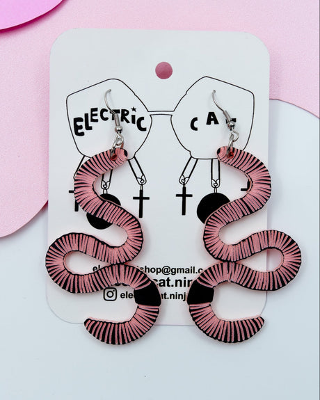 A pair of black and pink striped acrylic earrings designed to resemble earthworms, displayed on a white card with 'Electric Cat' branding.