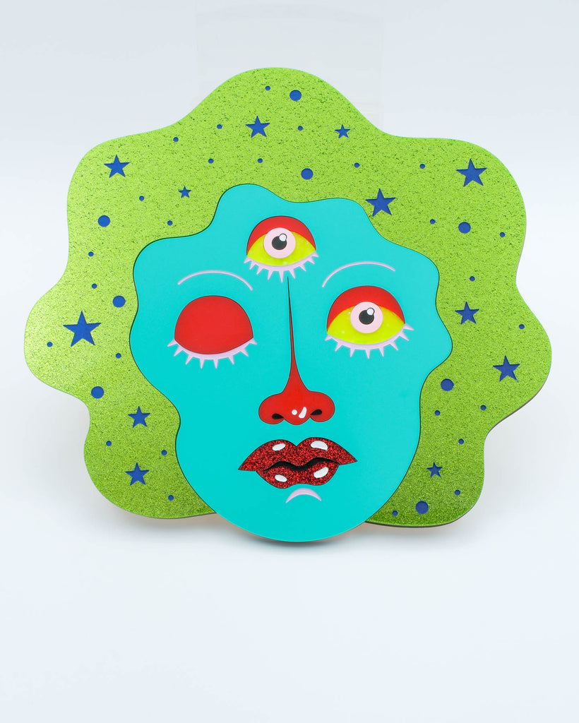 Colorful pop surrealism wall art featuring a teal three-eyed face with one eye closed and sparkling green background, art by Electric Cat.