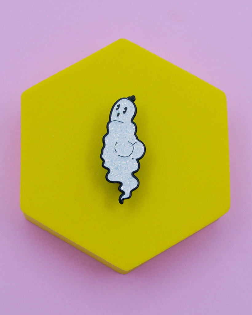 White glitter ghost soft enamel pin with black outline displayed on a yellow hexagon background, designed by Electric Cat.