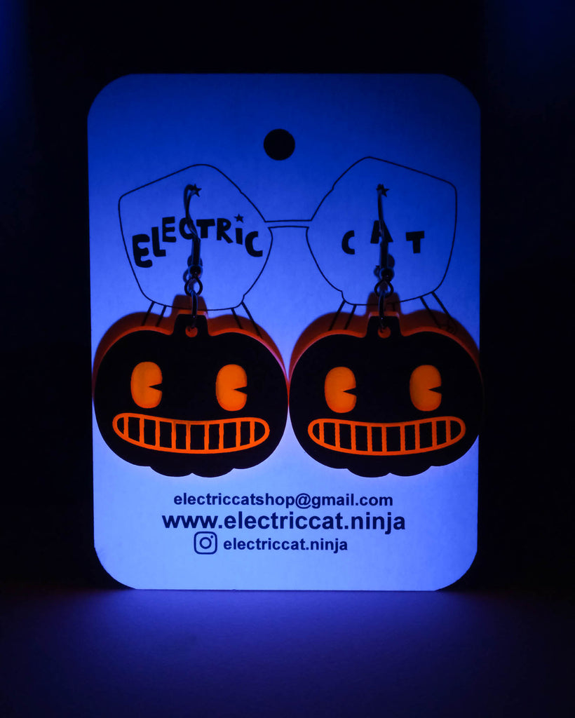 Glowing blue card with pumpkin-shaped earrings on a dark background