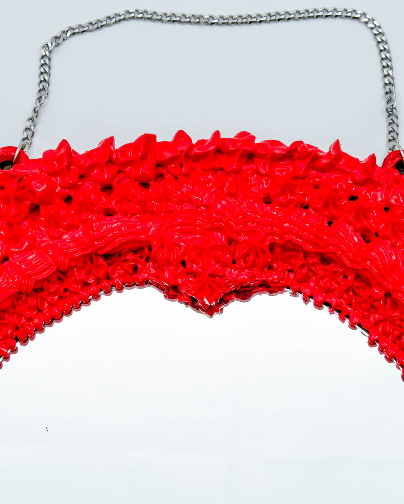 Red devil-themed mirror with sculpted frosting details, horns, and long satin ribbon bow, art by Electric Cat.
