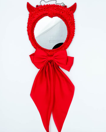 Red devil-themed mirror with sculpted frosting details, horns, and long satin ribbon bow, art by Electric Cat.