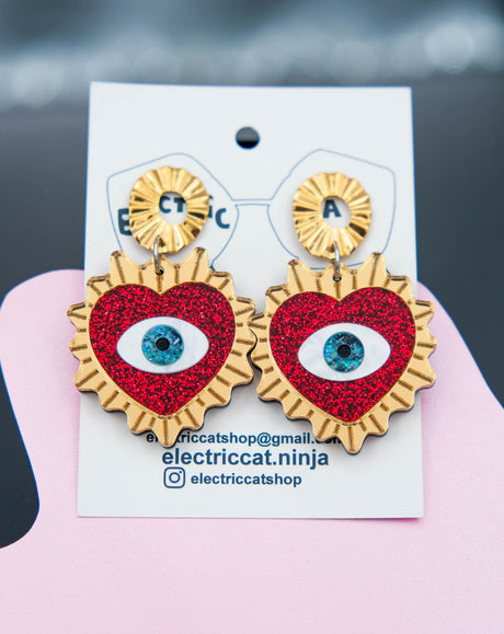 Heart-shaped earrings with eye design on a branded card