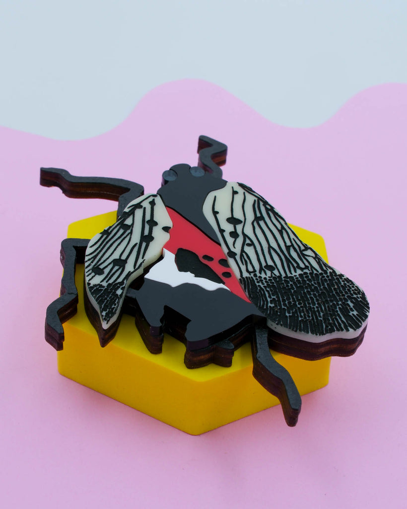 Handmade laser-cut acrylic and wood art piece showing a squashed spotted lanternfly with red and black markings, designed by Electric Cat.