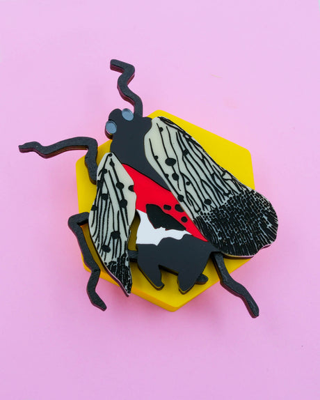 Handmade laser-cut acrylic and wood art piece showing a squashed spotted lanternfly with red and black markings, designed by Electric Cat.