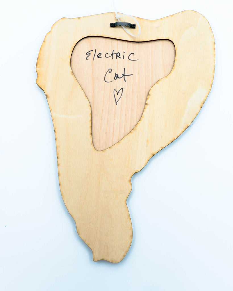 Wooden product shaped like a steak with 'Electric Cat' and a heart drawn on it, on a light blue background.