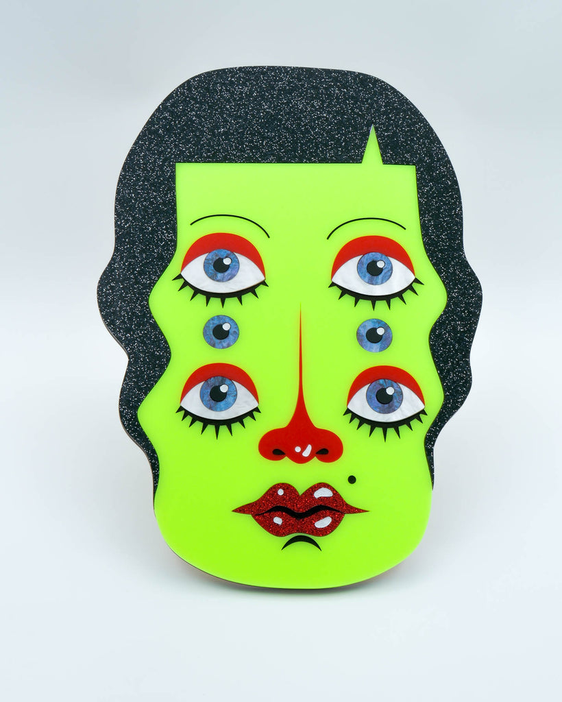 Handmade acrylic wall art featuring a neon green face with six eyes, black glitter hair, and red accents, art by Electric Cat.
